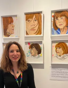 Clémence Devienne, souriante, devant sa série de portraits de Gisèle Pelicot accrochée au mur