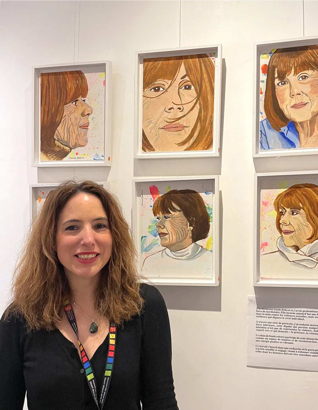 Clémence Devienne, souriante, devant sa série de portraits de Gisèle Pelicot accrochée au mur