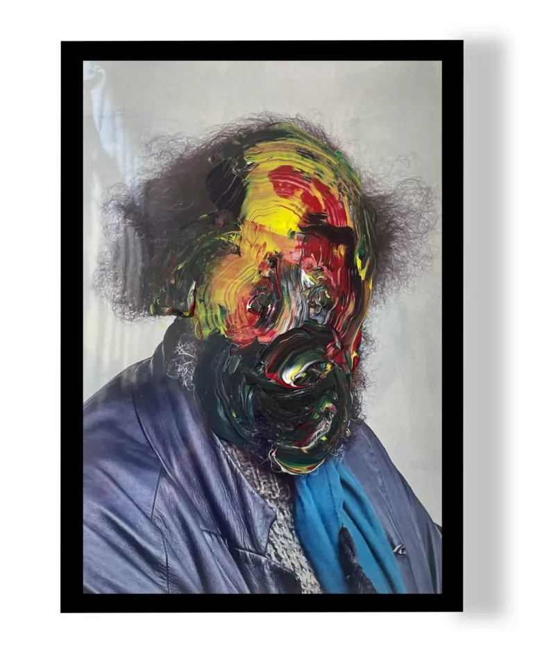 Eric Guilbert : photographie d'un homme barbu aux cheveux bouclés, le visage recouvert de tourbillons de peinture noire, rouge et jaune, dans un cadre noir