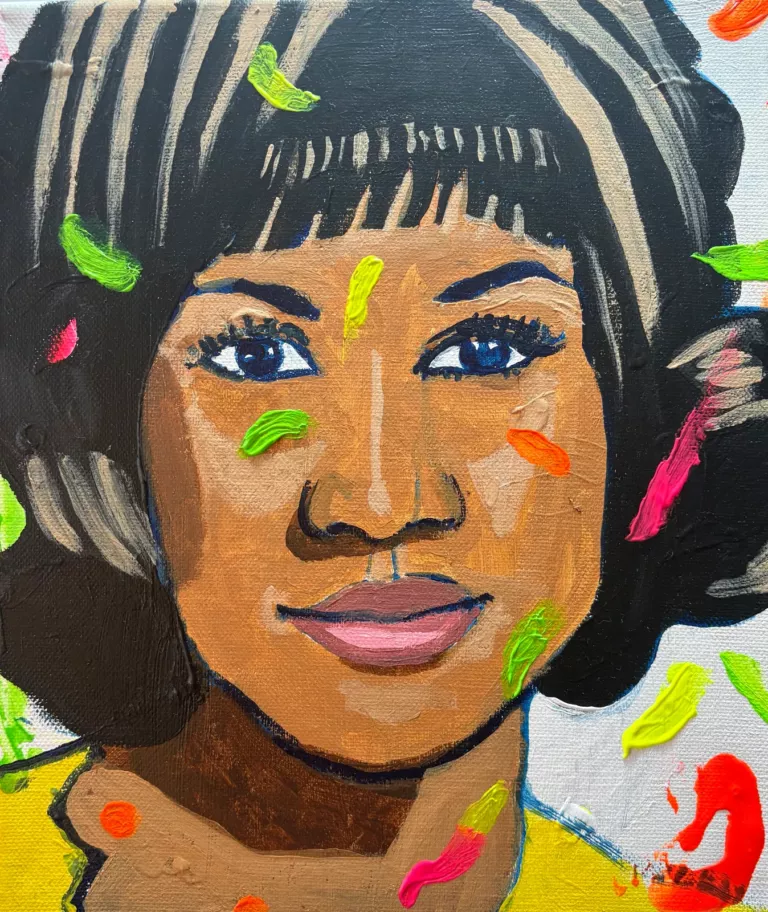 Portrait d'Aretha Franklin : visage souriant, frange noire, haut jaune, éclaboussures de peinture fluo verte, rose et orange
