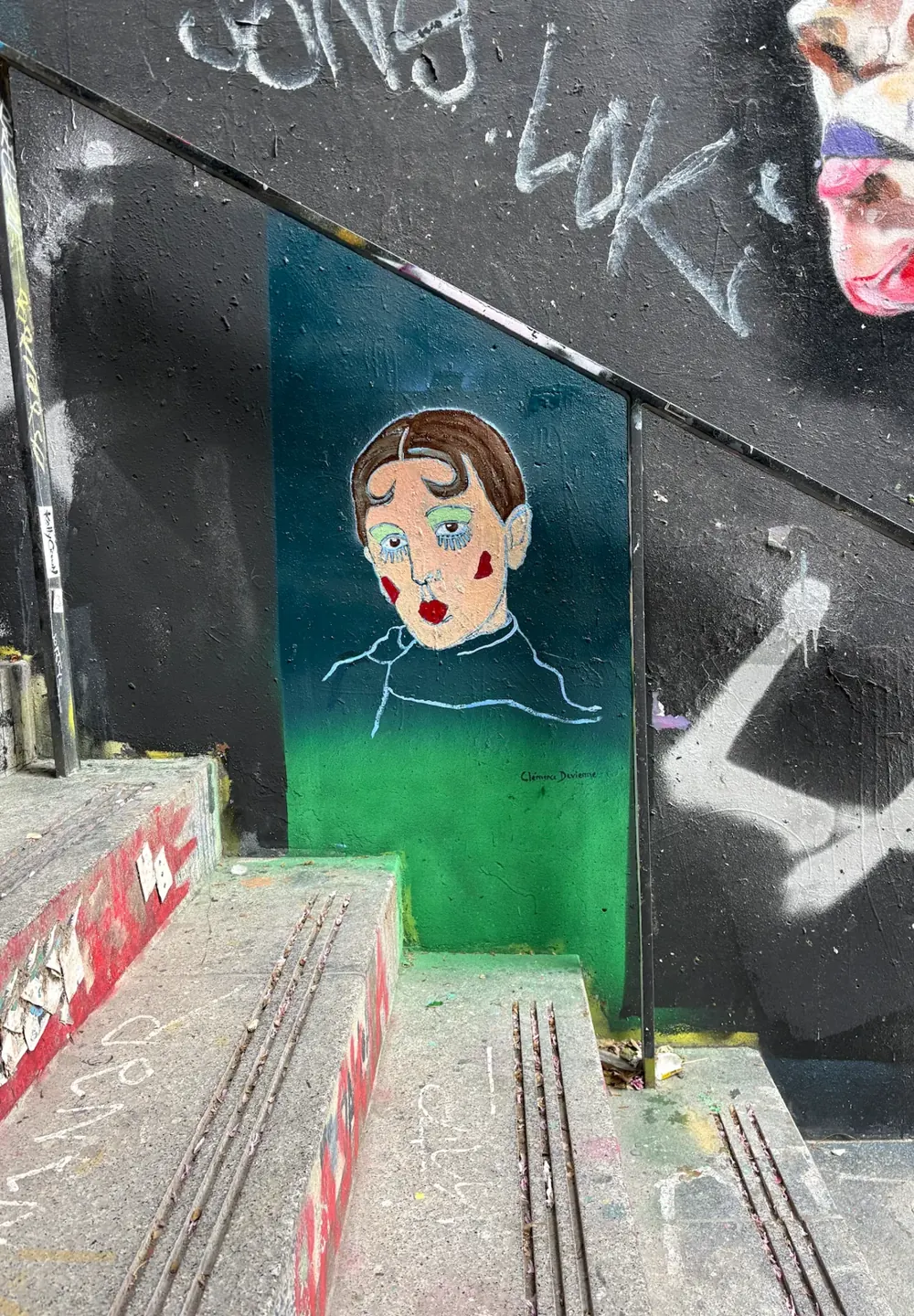 Portrait de Claude Cahun peint à la bombe et au pochoir au Lavomatik, haut lieu du street art à Paris : un mur noir couvert de graffitis, au-dessus d'un escalier